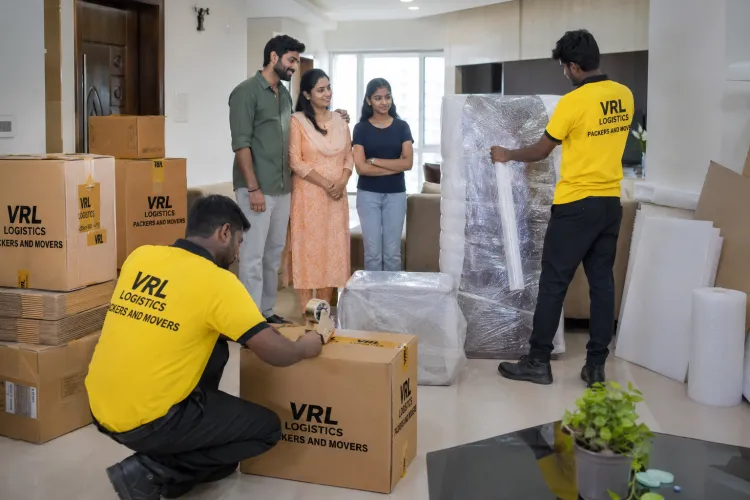 Movers wrapping furniture in bubble wrap and sealing branded VRL Logistics boxes during a home packing service in Chennai